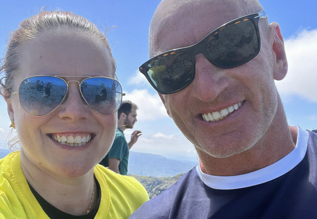 Christine with Gareth Thomas on the summit with blue sky behind them