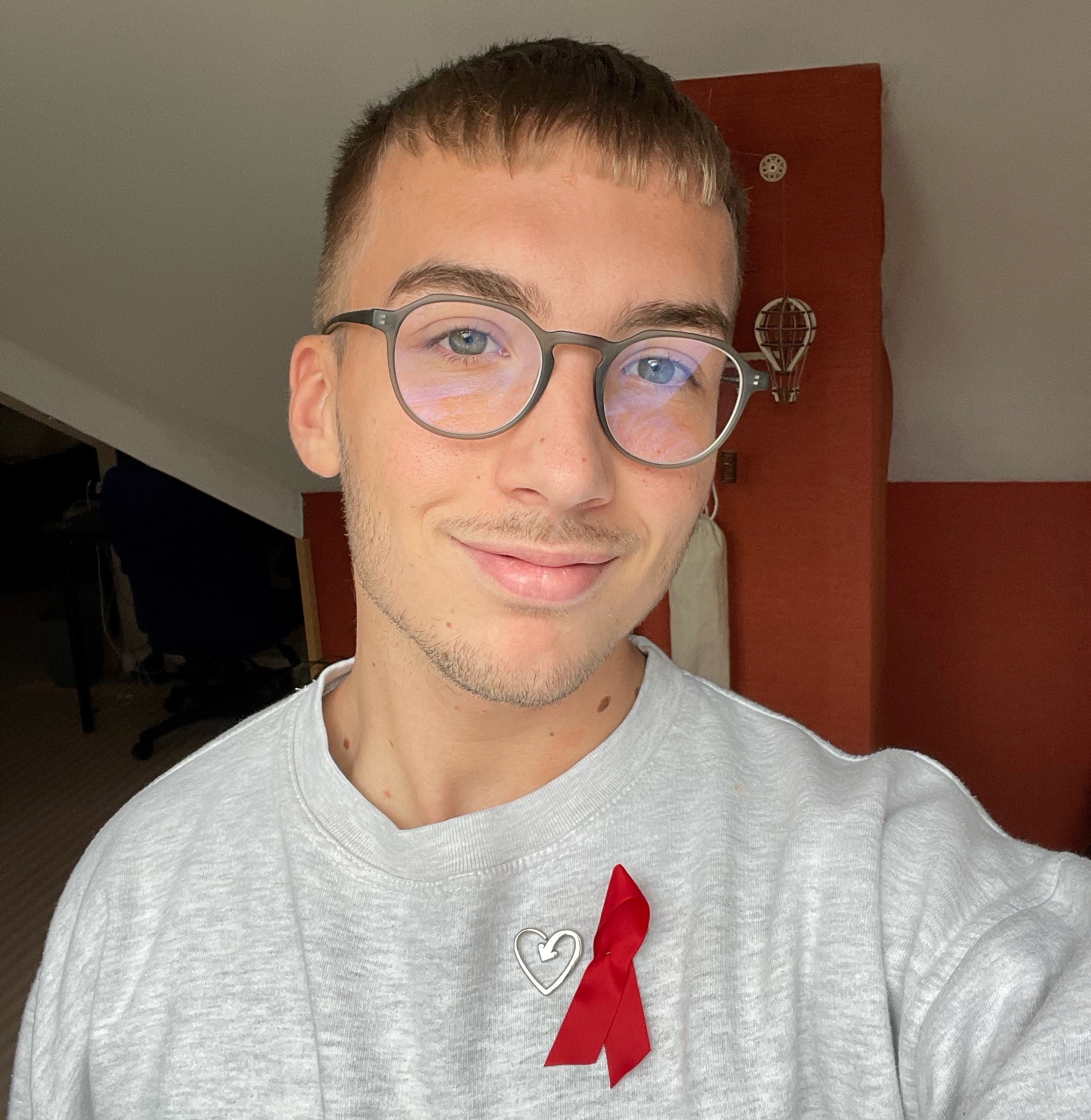 Dylan smiling indoors wearing red ribbon