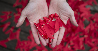 A hand holding red ribbons