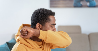 Man coughing into arm Man coughing into arm