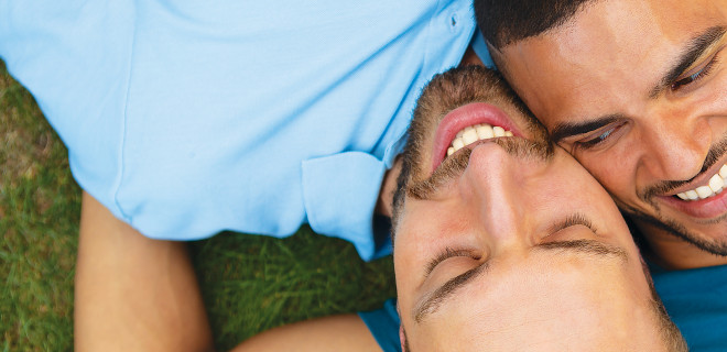Two men lying together on grass