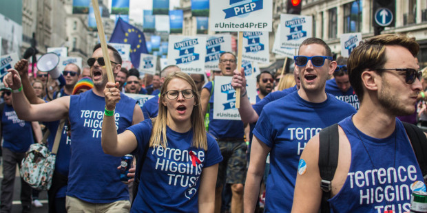 Terrence Higgins Trust staff and volunteers with banners and signs marching during Pride