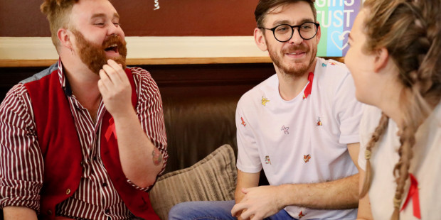 People wearing red ribbons chatting on the sofa